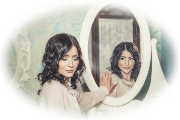 Woman looking away from a mirror while her reflection looks at her